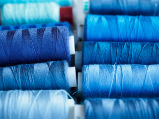Lots of bobbins of thread for sewing. Threads of blue shade.