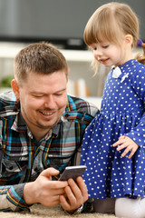 Cute little girl on floor carpet with dad use cellphone calling mom portrait. Life style apps social web network wireless ip telephony concept
