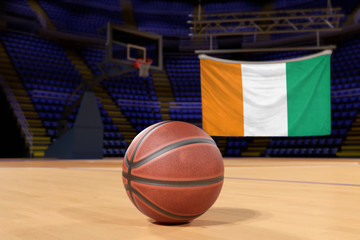 Naklejka premium Ivory Coast flag and basketball on Court Floor