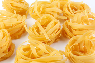 Italian rolled Raw noodles. Pasta on white background . Egg homemade dry ribbon noodles, long rolled macaroni or uncooked spaghetti isolated.