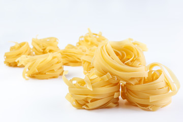 Italian rolled Raw noodles. Pasta on white background . Egg homemade dry ribbon noodles, long rolled macaroni or uncooked spaghetti isolated.