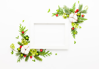 Christmas composition  with photo frame, cotton flower, branches of spruce and holly with red...