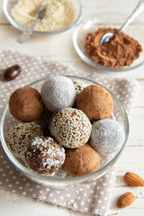 Energy balls with cocoa and sesame seeds in a glass bowl on a white background