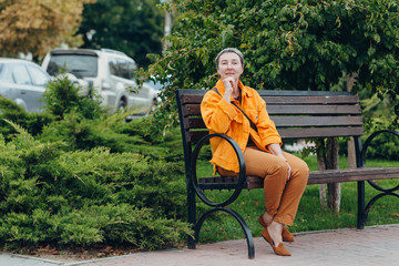 Happy stylish stylish fashionable senior woman sitting on a bench in the city streets