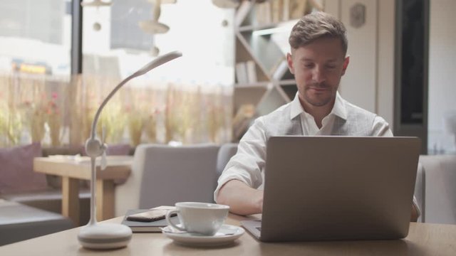 Businessman sitting and working in a cafe. Man using computer devices. Business and entrepreneurship.