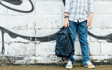 Front view of cool looking and stylish teenager's body stand and pose against white brick wall with...