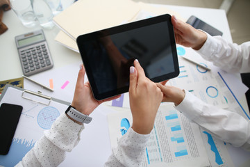 Close-up of workers hands holding tablet and tapping screen. Colleagues discussing new business...