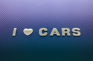 Concept of love of cars, driving. Letters on carbon fiber background