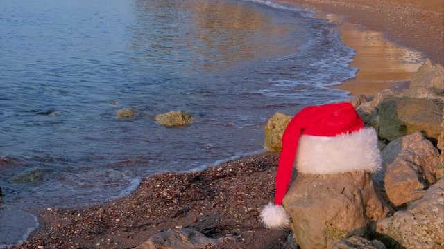 Christmas Santa Claus hat on tropical sandy beach with calm waves. Winter holidays. New Year celebration on island. Concept
