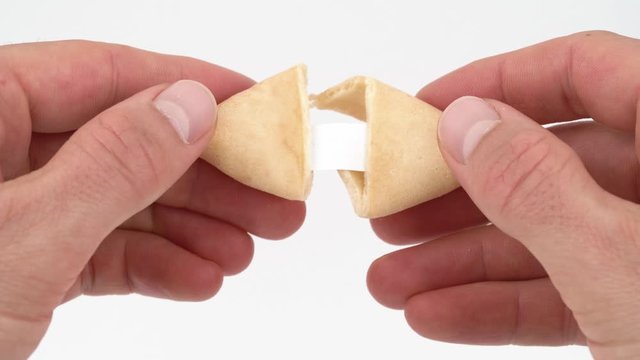 Close-up of male hands opening a fortune cookie with a card inside. Isolated, on white background.