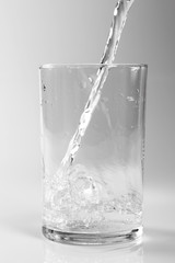 Pouring clear water into glass. Isolated on white background.