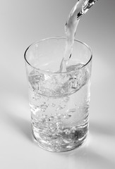 Pouring clear water into glass. Isolated on white background.