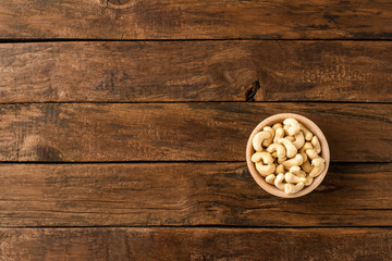 Roasted cashews in bowl on wooden table. Top view