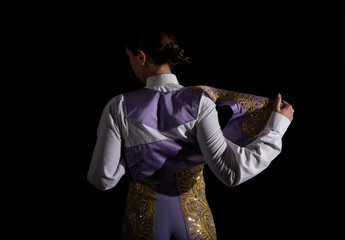 Woman bullfighter by dressing with vest on your back on a black background