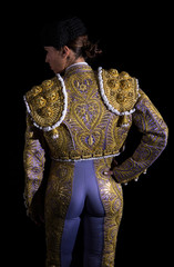 Woman bullfighter by dressing with vest on your back on a black background