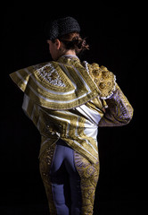 Woman bullfighter by dressing with vest on your back on a black background