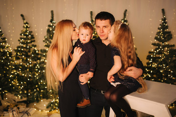 Christmas Family. Portrait of dad, mom, daughter and son sitting at home by the Christmas tree. Happy family. Christmas mood