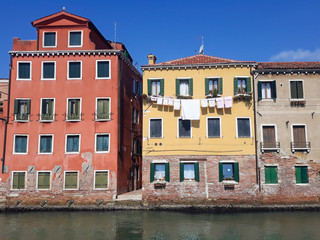 Fototapeta na wymiar Colorful houses with drying clothes near canal in Venice, Italy