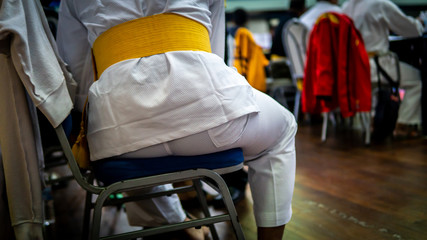 Young man wearing a fully white and yellow belt, full dress or uniform for martial arts referees.