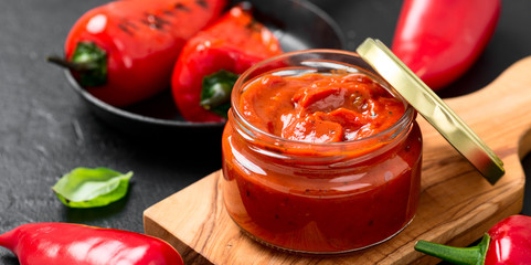 Grilled red pepper sauce (lutenica)  in glass jar with toasted bread.