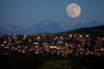 small village in high mountains and full moon in the sky 