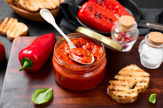 Grilled red pepper sauce (lutenica)  in glass jar with toasted bread.