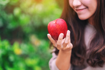 A beautiful woman holding a fresh red apple in hand