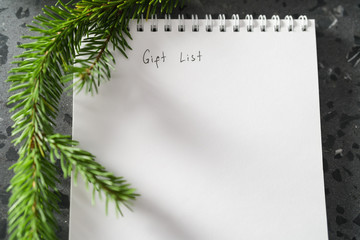 Notepad with gift list and spruce twig on terrazzo countertop