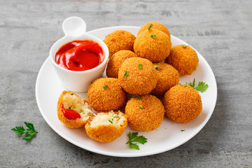 Homemade Fried Risotto Arancini stuffed with cheese, served with tomato sauce.