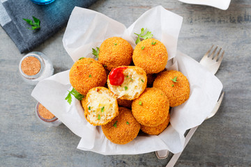 Homemade Fried Risotto Arancini stuffed with cheese, served with tomato sauce.
