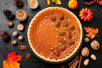 Festive Homemade Pumpkin Pie decorated with pecan nuts and pumpkin seeds.