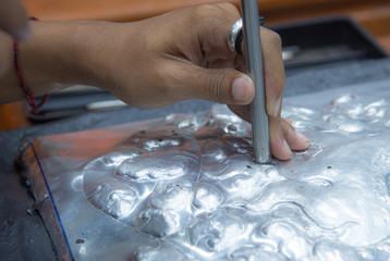 Fototapeta na wymiar Man artisan hand holding tool making extraordinary silver plate carving art wotk.