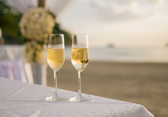 Two glasses of champagne on wedding table in the sunset beach