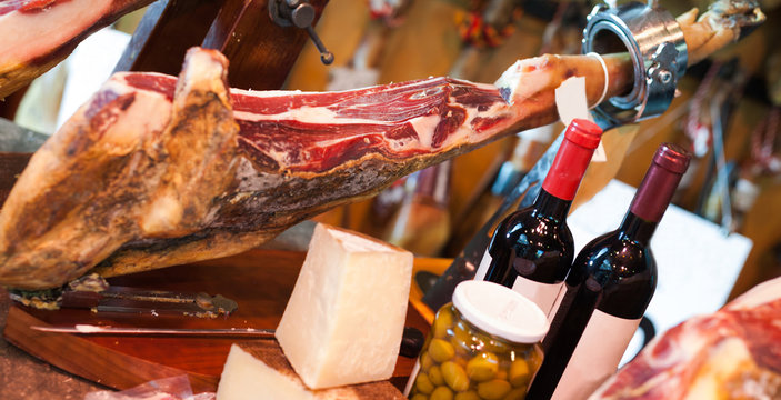 Still life of spanish pork jammon on holder, bottles of wine cheese and olives