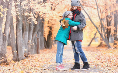 Obraz premium Girl in autumn city park in leaf fall. Young beautiful mother with her daughter on nature. A girl in a hat walks in the park.