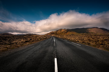 An empty Icelandic road leads through a mountain range