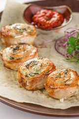 chicken breast roll stuffed with cheese and herbs and tomato sauce on brown plate