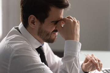 Young manager suffering from eye strain or dry eyes syndrome.