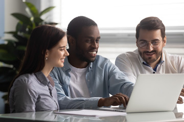 Smiling african american team leader working on computer with colleagues.