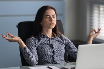 Young female worker making yoga breathing exercises.