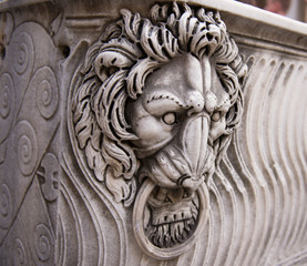 Fototapeta na wymiar antique stone carving a lion's head with a ring in his teeth