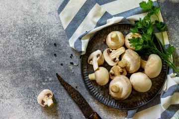Champignons. Fresh white mushrooms in bowl on stone background. Top view of a flat lay. Free space for your text.