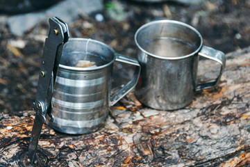 Two metal mugs on tree. Adventure in nature, tourism. Tea party in extreme conditions.