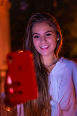 A young brunette with a pink phone writing a message to her best friends one night out