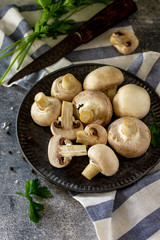 Champignons. Fresh white mushrooms in bowl on stone background.