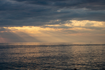 Naklejka na ściany i meble The rays of the sun make their way through gloomy clouds over the Black Sea