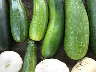 Green zucchini; Elongated green vegetable; Fresh picked green courgette offered at farmer's market; Summer squash