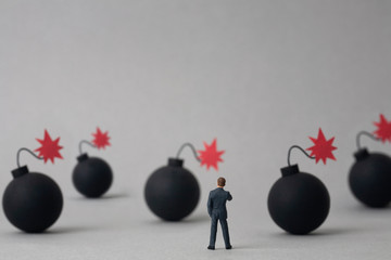 Multiple bombs and miniature businessman on grey background