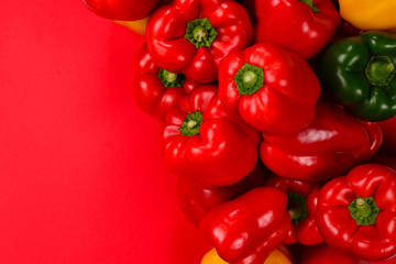 Fresh red, yelow, green bell pepper on a red background.