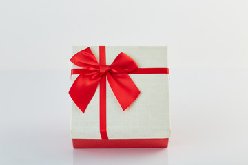 White gift box with red ribbon bow on white